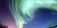 The magnificent spectacle of the Aurora Borealis, or northern lights, glows in the northern sky above Bear Lake near Eielson Air Force Base, Alaska. Shaped by the Earth’s magnetic field, this light is produced by radiation spewed from solar storms.