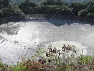 <b>Figure 27.28</b> A 305-m-diameter natural bowl at Arecibo in Puerto Rico is lined with reflective material, making it into a radio telescope. It is the largest curved focusing dish in the world. Although "D" for Arecibo is much larger than for the Hubble Telescope, it detects much longer wavelength radiation and its diffraction limit is significantly poorer than Hubble’s. Arecibo is still very useful, because important information is carried by radio waves that is not carried by visible light.